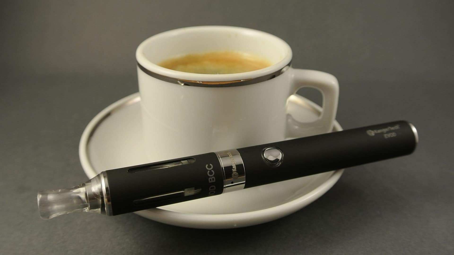 Méthode pour arrêter de fumer : Cigarette électronique posée à côté d'une tasse de café vide sur une soucoupe.