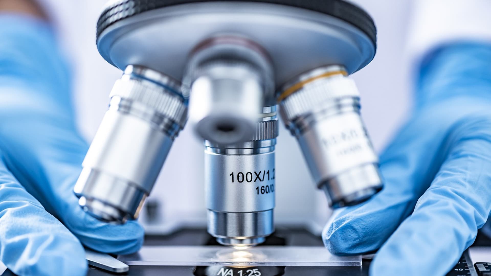 Scientifique ajustant un microscope pour des tests ADN en laboratoire.