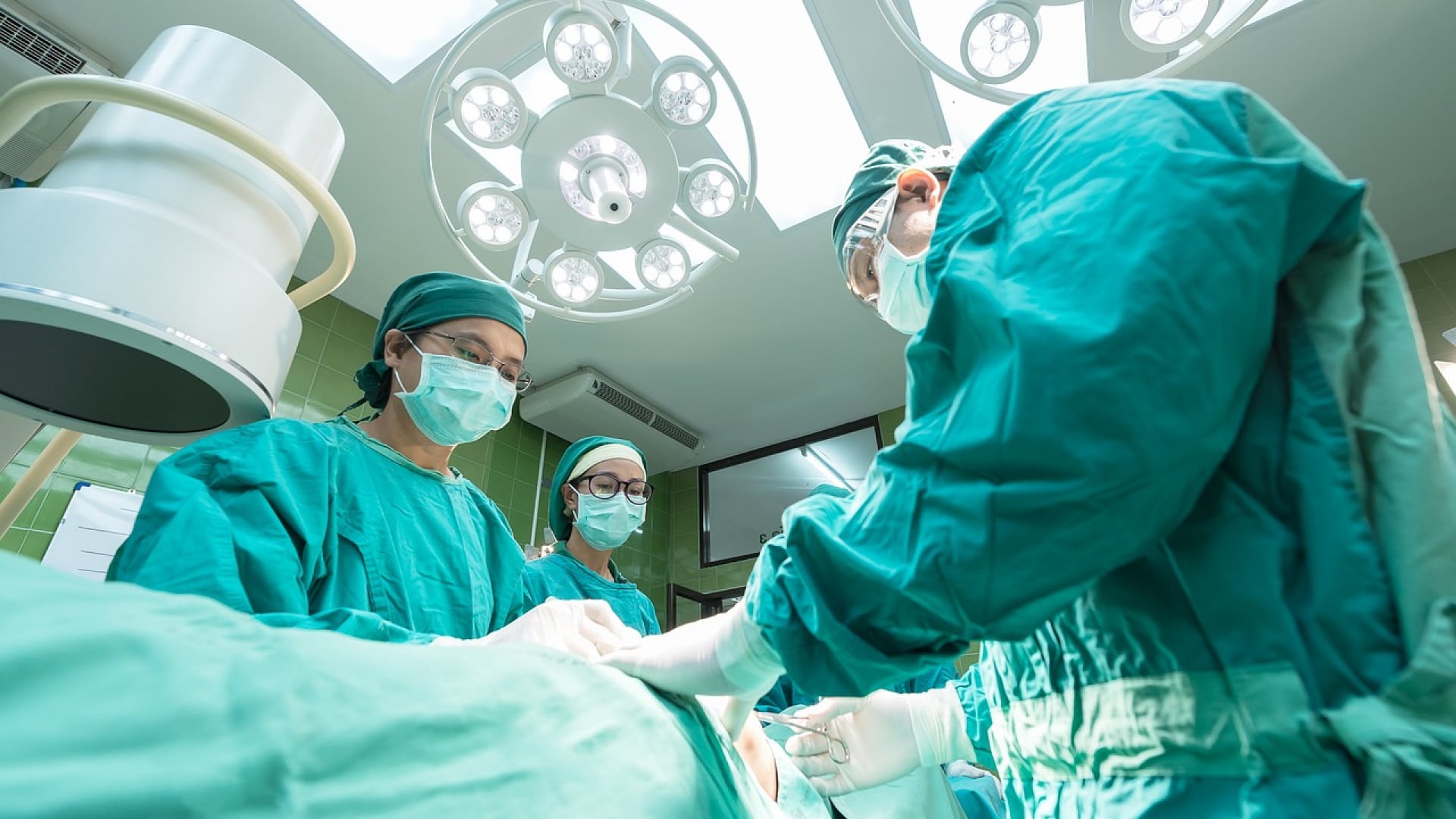 Personnel médical effectuant une chirurgie sous les lumières de la salle d'opération.