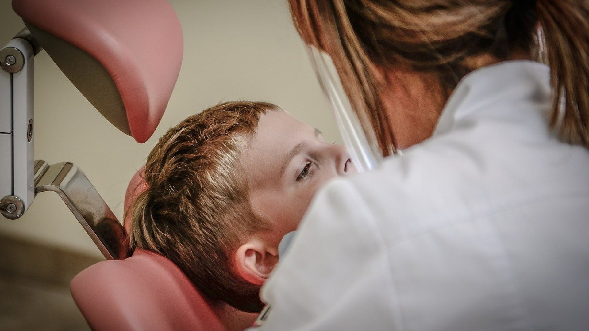Un enfant patient qui attend un examen dentaire alors qu'il est assis dans le fauteuil du dentiste envisage de choisir une mutuelle santé.
