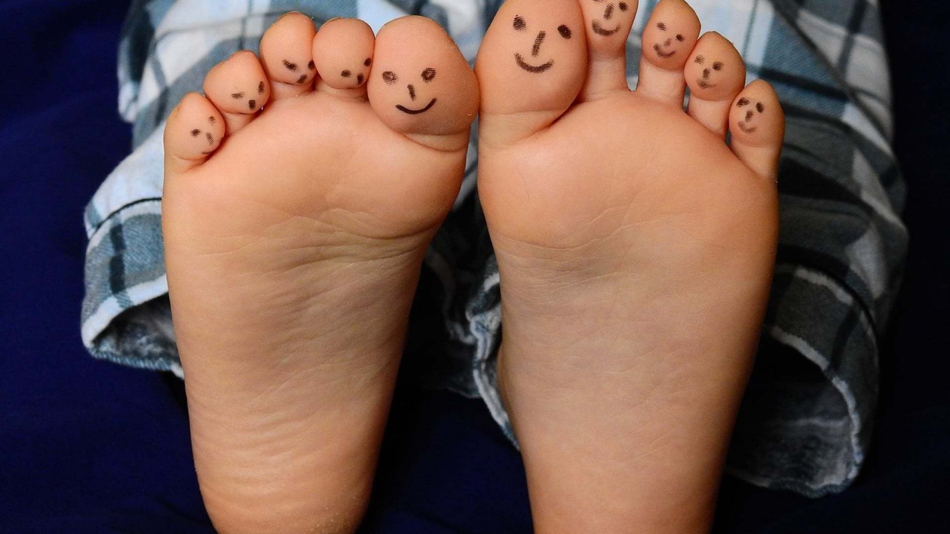 Les pieds nus d'une personne avec des visages souriants dessinés sur les orteils, présentant des astuces créatives.