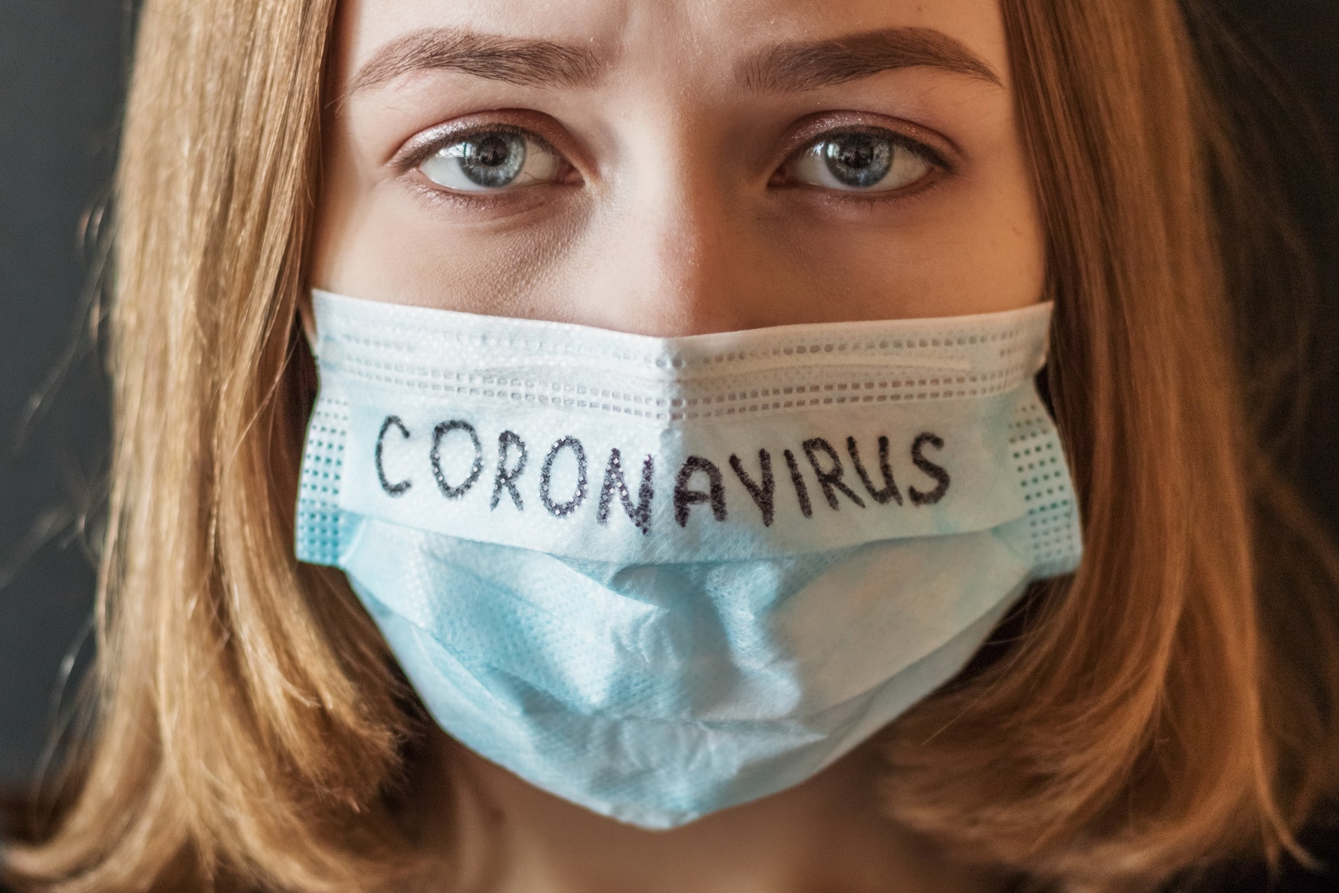 Femme portant un masque de protection sur lequel est écrit le mot « coronavirus ».