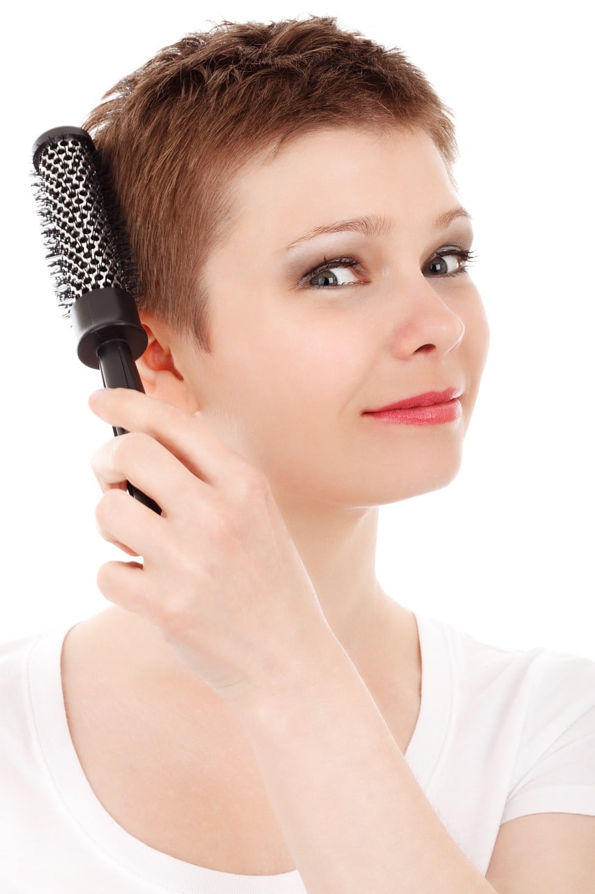 Femme se brossant les cheveux courts avec une brosse ronde.