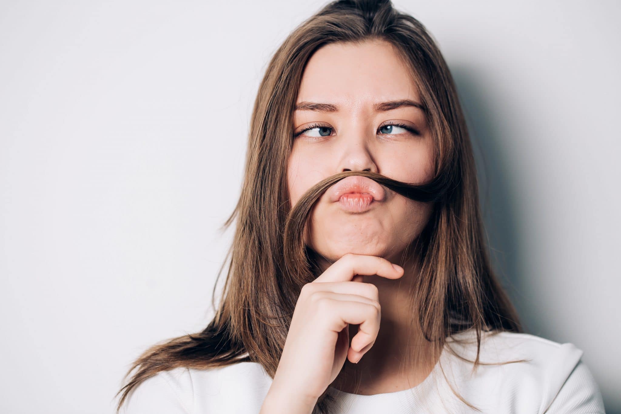 Jeune femme faisant une fausse moustache avec ses cheveux tout en réfléchissant à la façon de calculer le cycle menstruel de son fils.