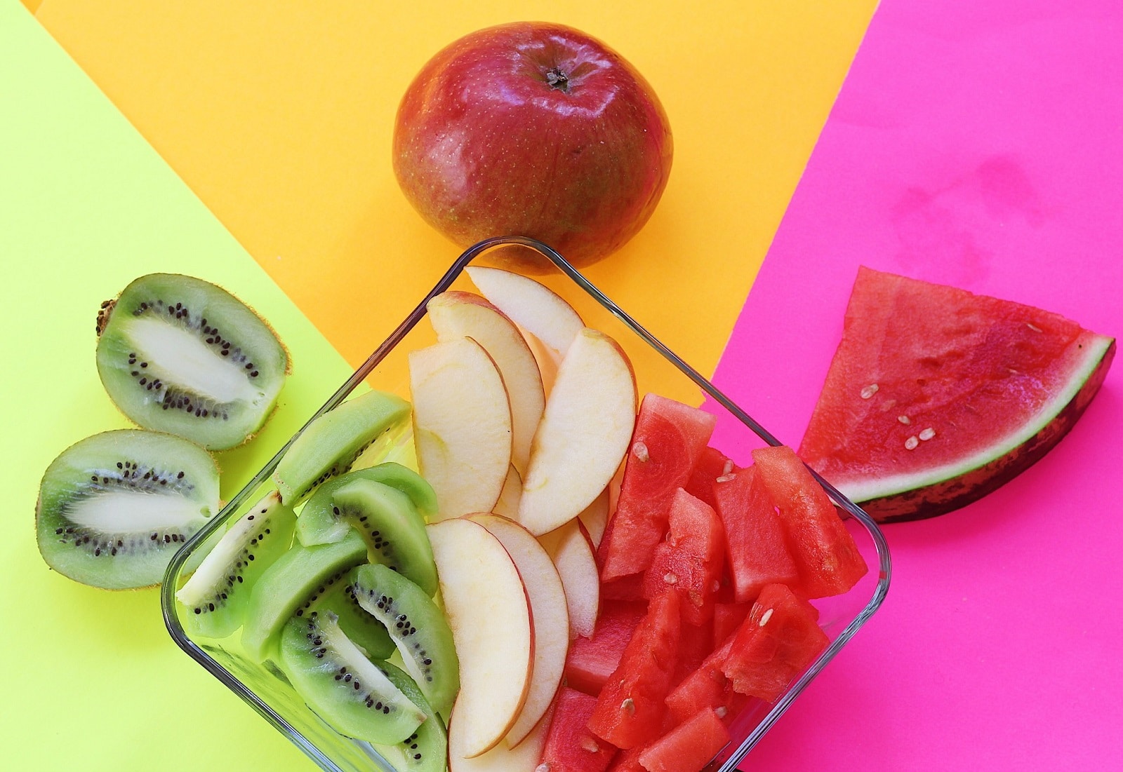 Assortiment de fruits frais sur fond coloré, riches en vitamines pour contrecarrer les symptômes de carences.