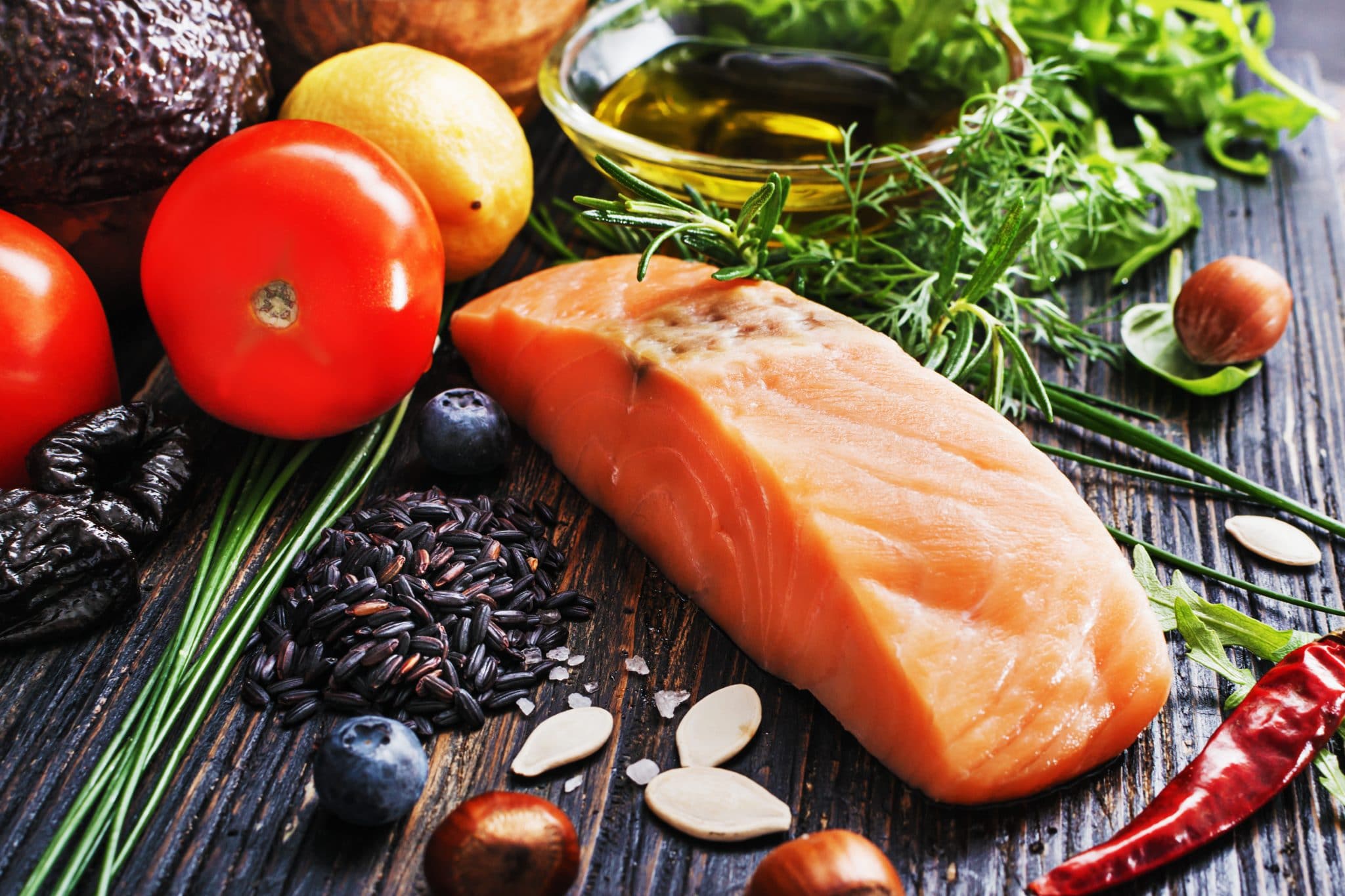 Filet de saumon frais entouré d'un assortiment d'ingrédients sains sur une surface en bois, servant de guide ultime pour mieux connaître une alimentation nutritive.