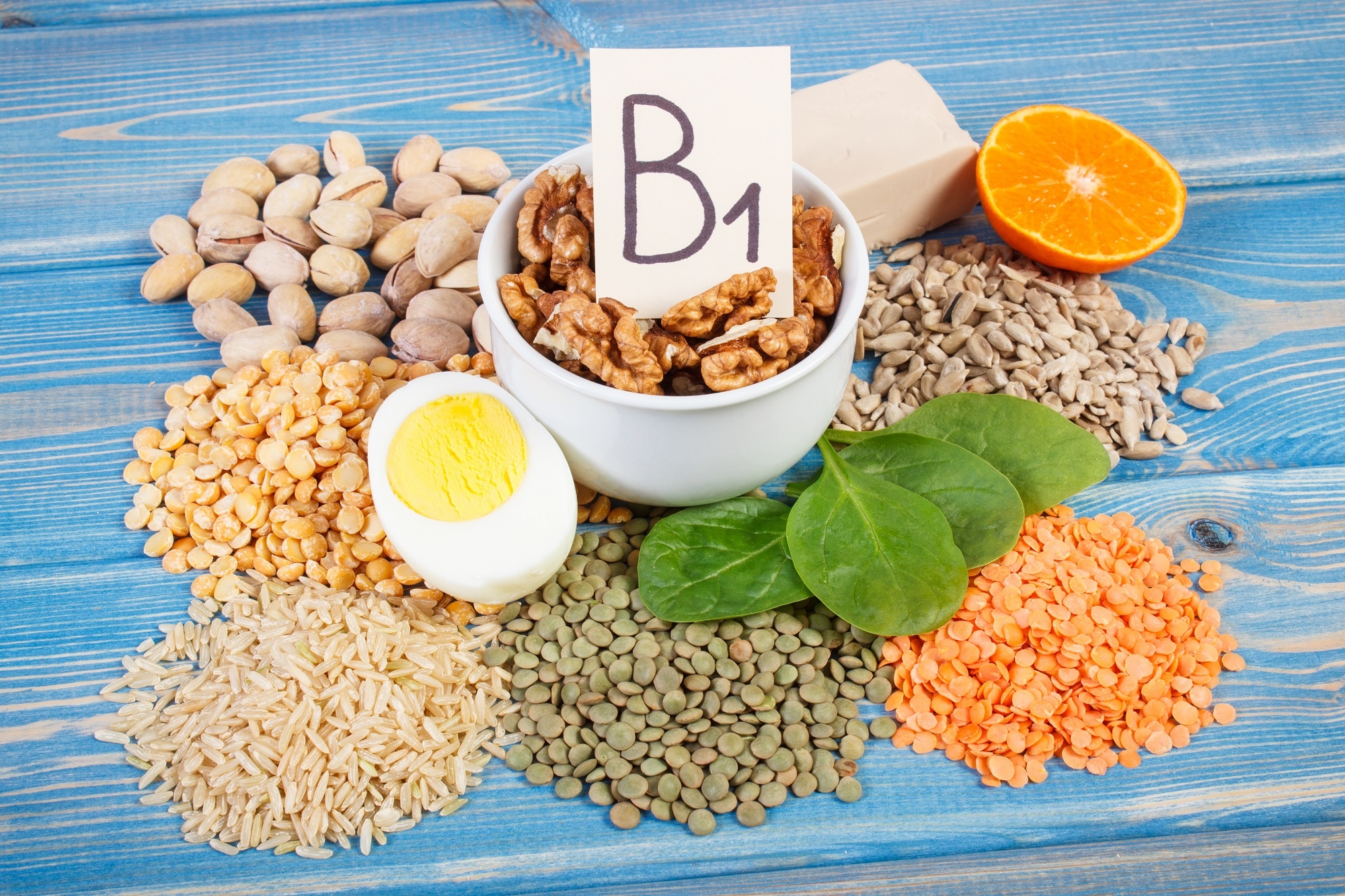 Divers aliments riches en vitamine B1 (thiamine) affichés sur une surface en bois bleue pour prévenir les symptômes de carence en vitamine B1.