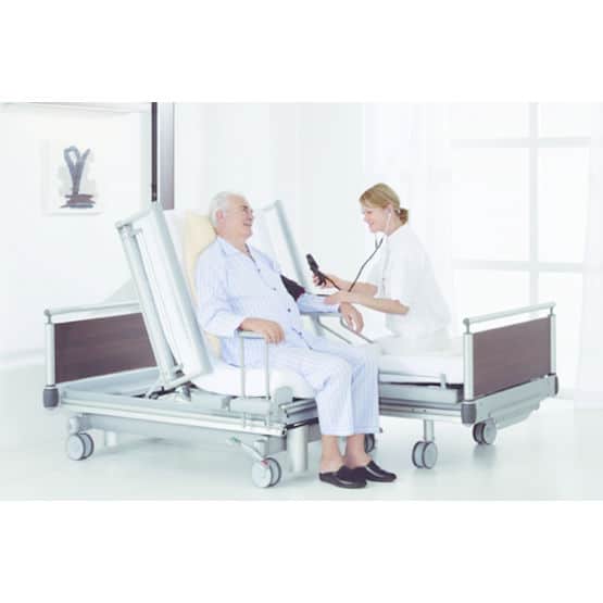 Un médecin discute avec un patient de sexe masculin assis sur un lit d'hôpital réglable.
