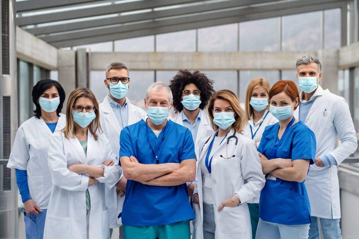 Un groupe de travailleurs de la santé portant des gommages et des masques faciaux posant pour une photo.