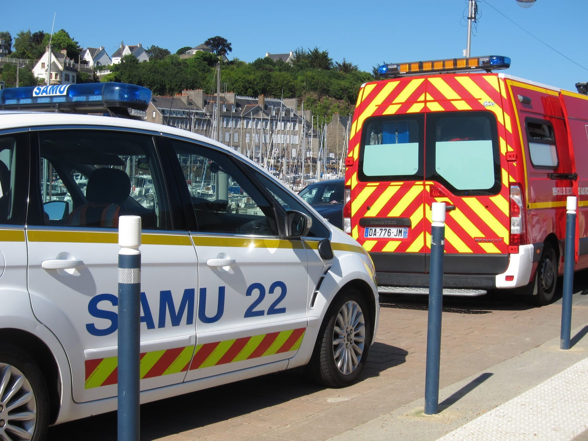 Des véhicules d'urgence, dont une voiture du Samu 22 et un camion de pompiers, garés près d'un front de mer, prêts à répondre à tout numéro d'urgence.