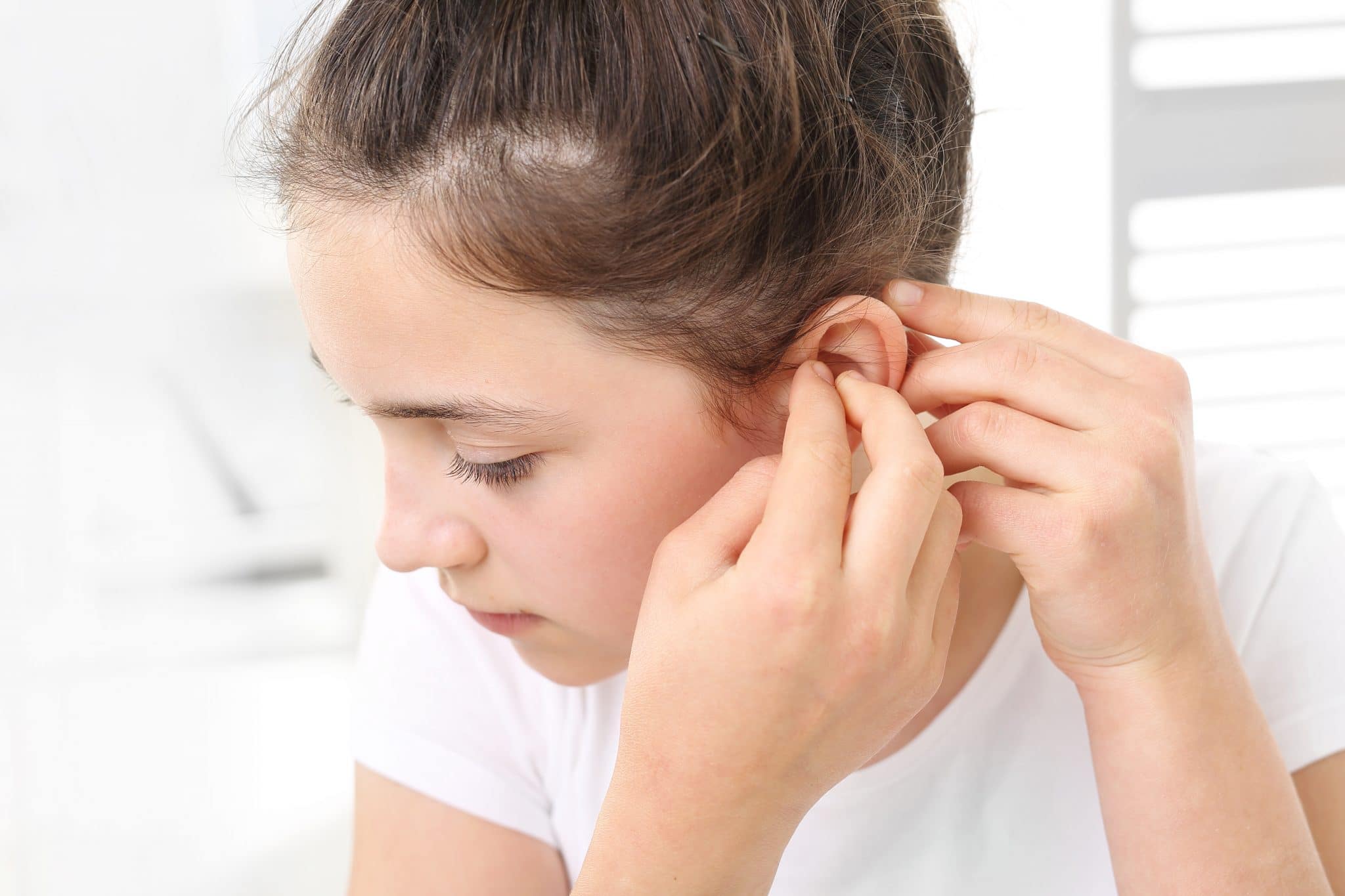 Une personne insérant un appareil de soins auditifs dans son oreille.