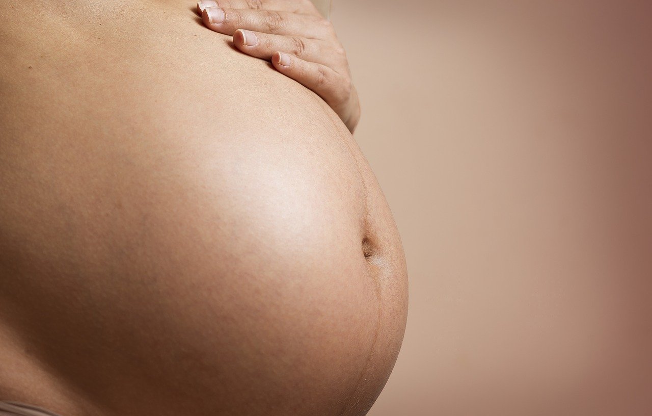 Une vue rapprochée du ventre d'une femme enceinte avec sa main reposante dessus, illustrant un moment de la grossesse.