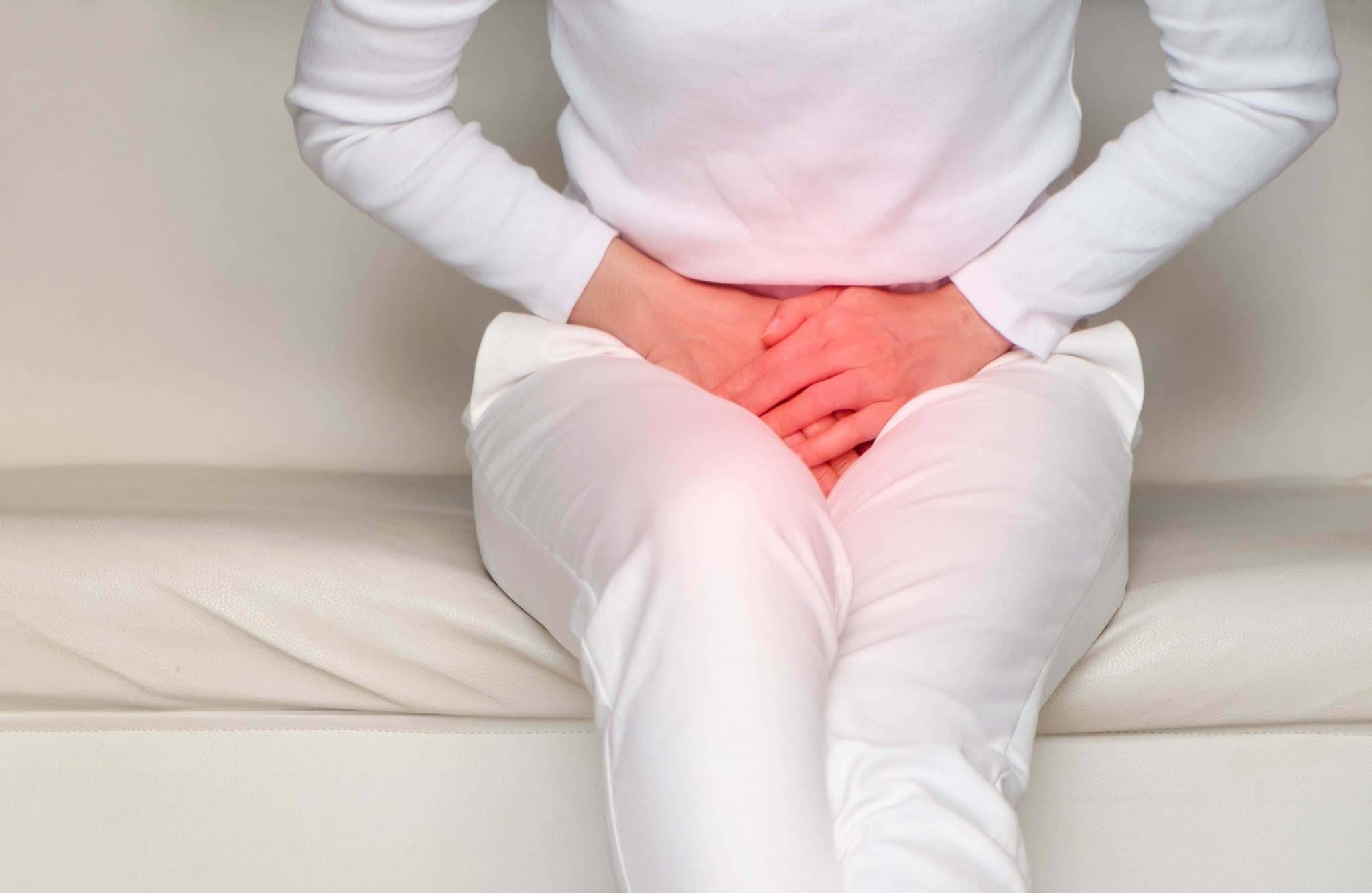 Personne souffrant de douleurs au bas du dos et de symptômes d'incontinence alors qu'elle est assise sur un canapé.