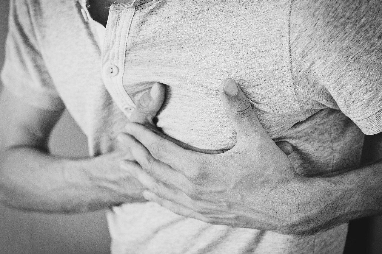 Une personne serrant sa poitrine avec une expression douloureuse, indiquant potentiellement un inconfort ou une douleur cardiaque, nécessitant éventuellement de prévenir un AVC.