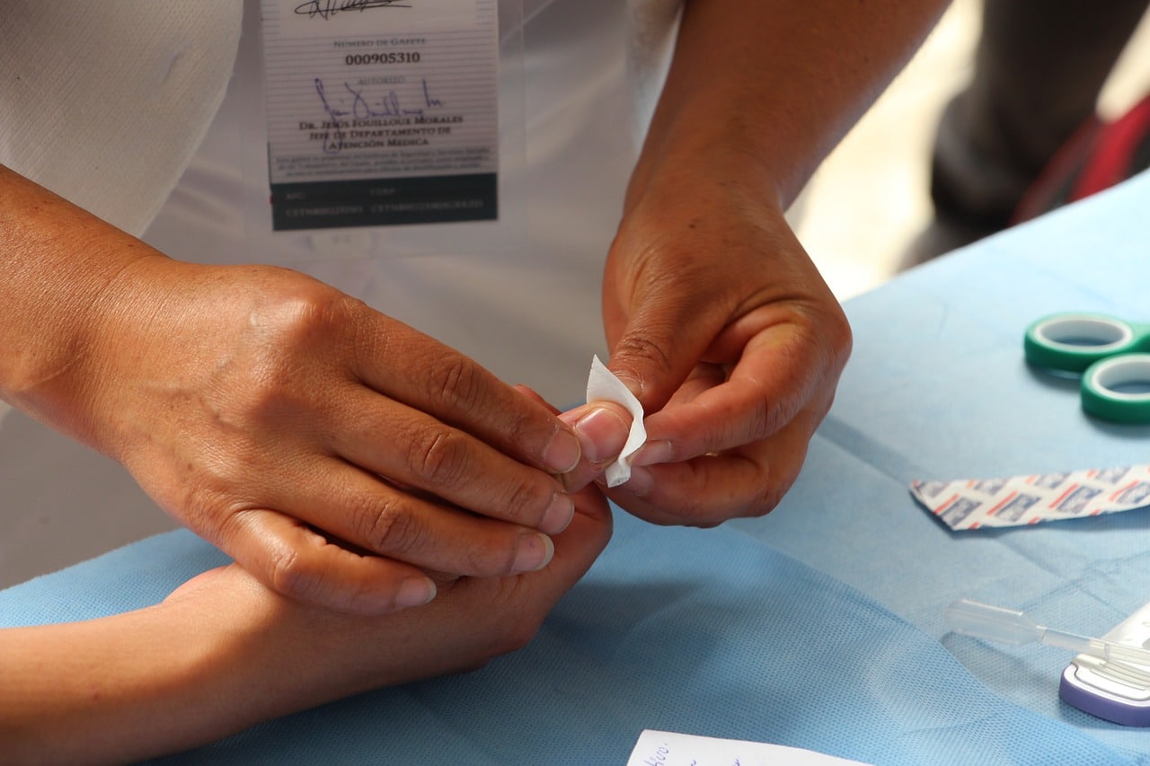 Professionnel de la santé appliquant un bandage sur le doigt d'un patient après une intervention.