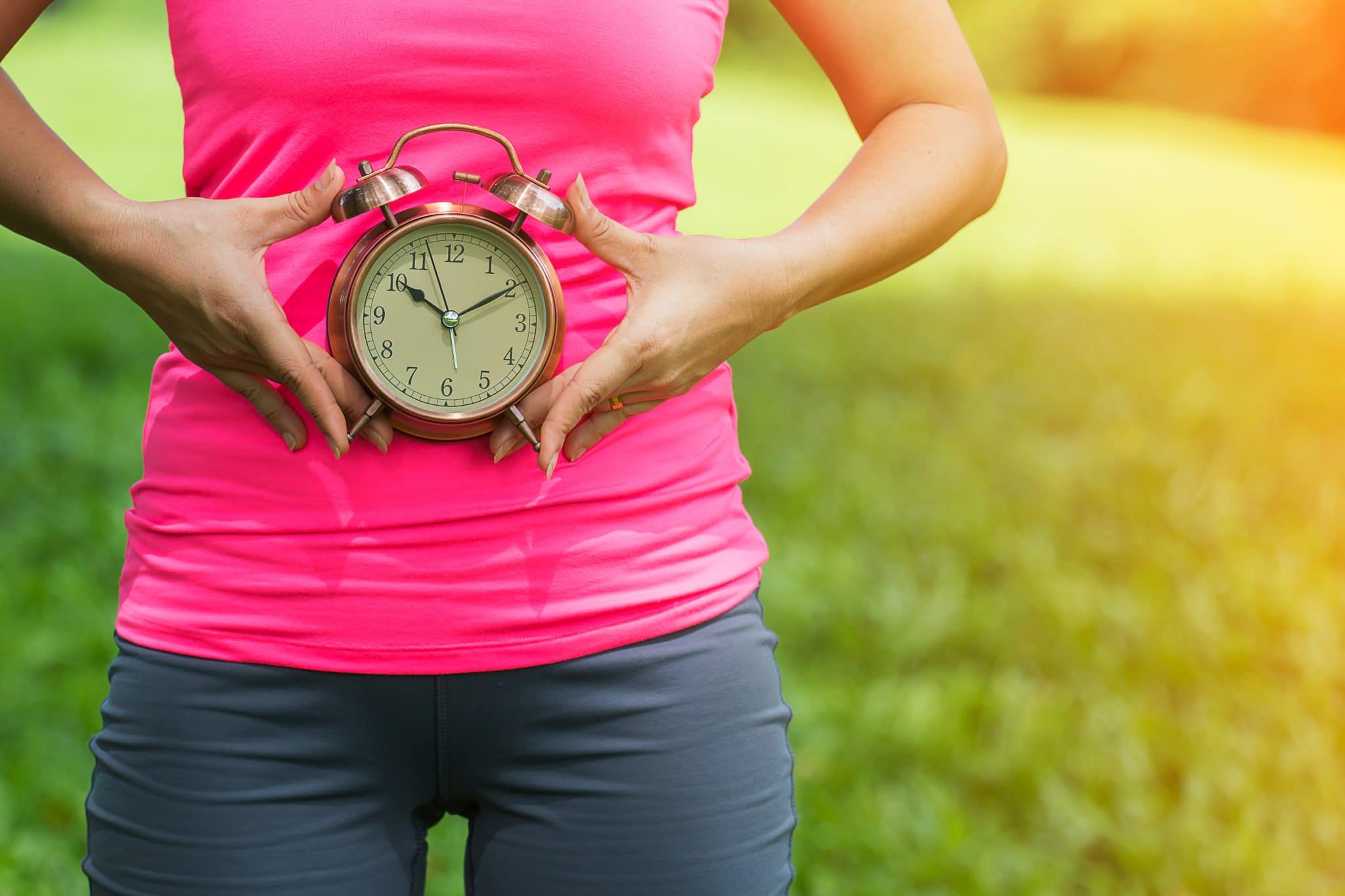 Femme tenant une horloge sur le ventre, symbolisant peut-être la durée des règles ou le cycle menstruel.
