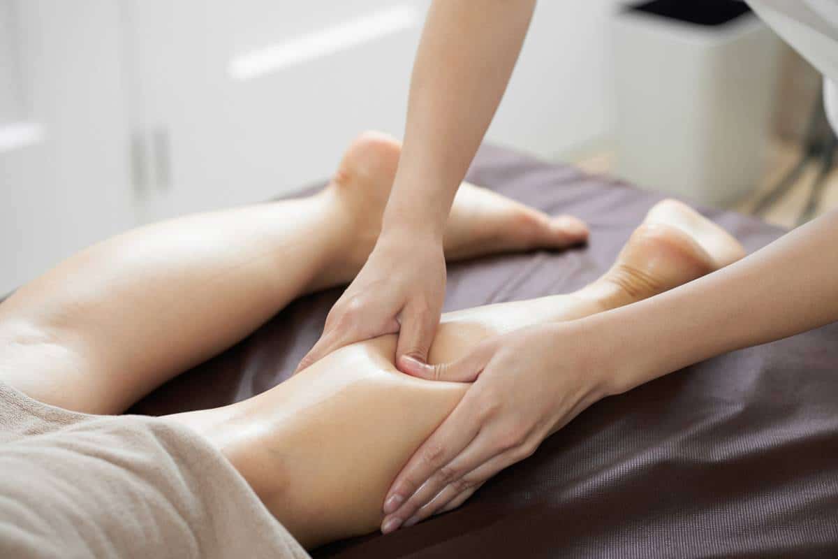 Une personne recevant un massage des jambes dans une salle de thérapie.