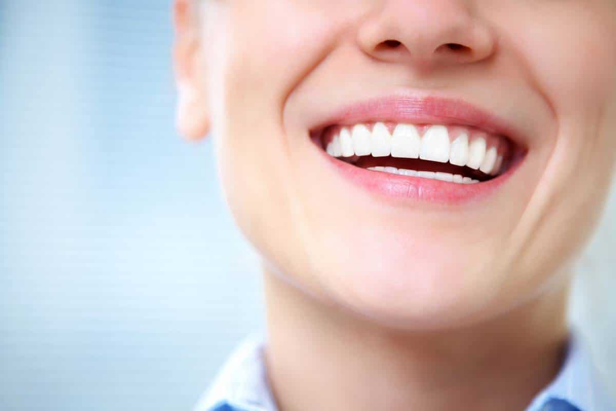 Gros plan de la bouche souriante d'une personne, montrant des dents blanches.
