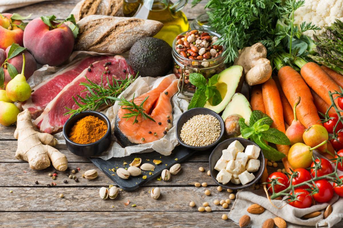 Assortiment d'aliments sains comprenant des fruits, des légumes, des viandes maigres et des céréales étalées sur une surface en bois pour mieux manger.