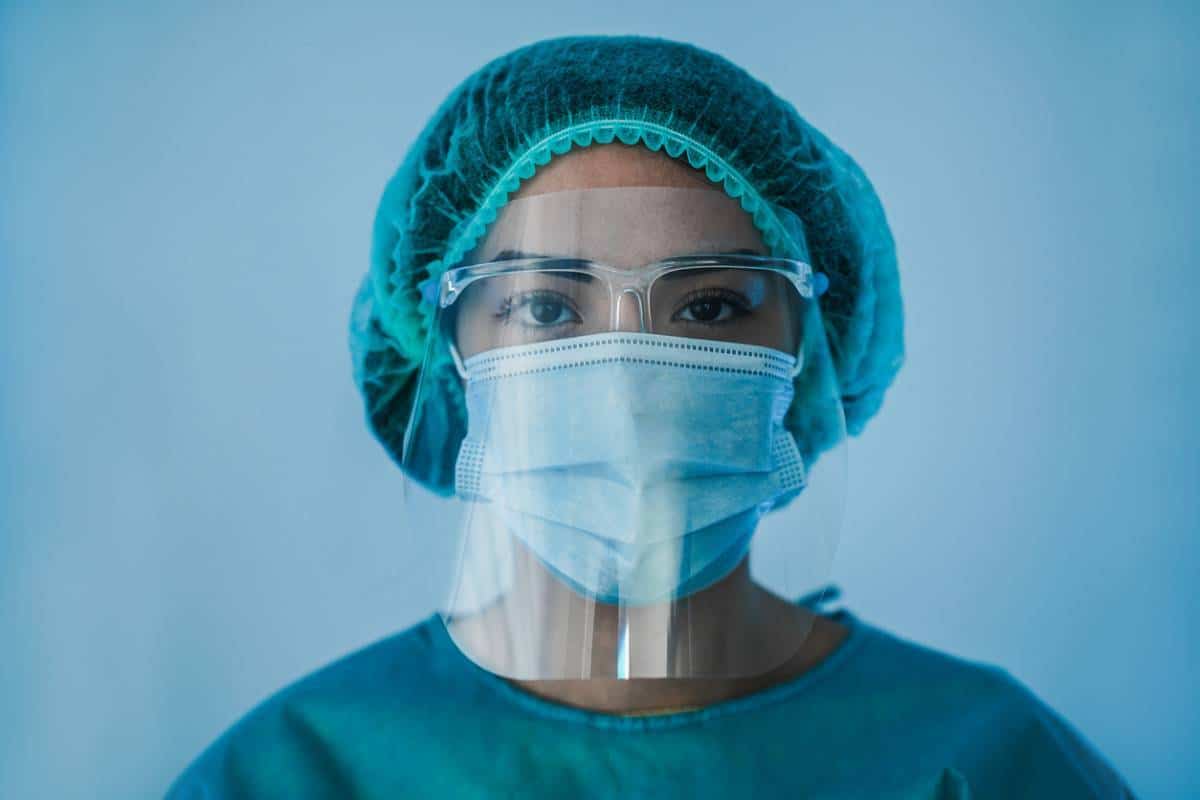 Professionnel de santé portant un équipement de protection, y compris un masque facial, une visière et un bonnet chirurgical pour le Covid-19.