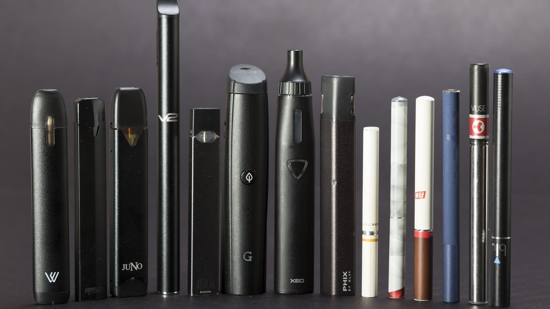 Divers types de cigarettes électroniques et stylos vape, pour débuter, alignés sur un fond sombre.