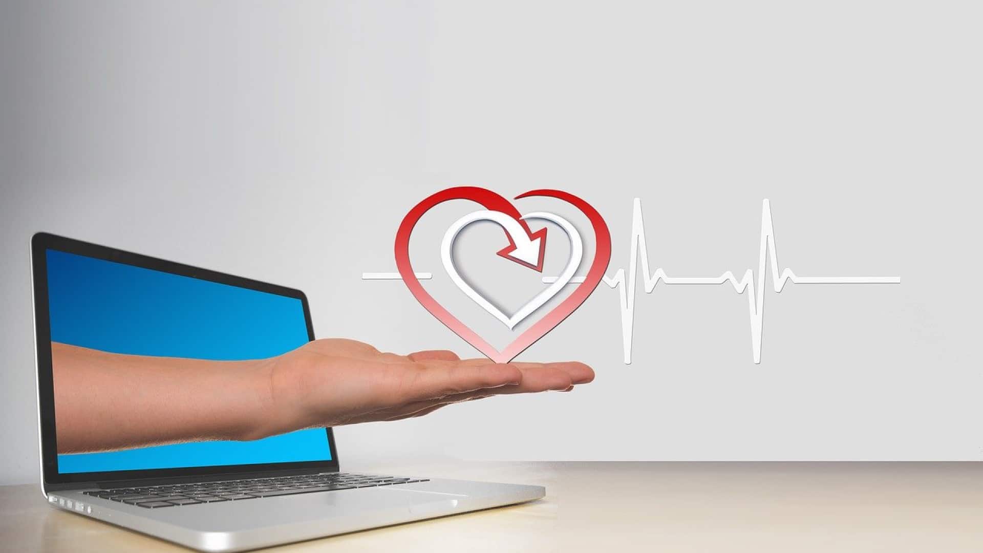 Une main ouverte s'étend d'un ordinateur portable affichant un cœur et une ligne ECG, symbolisant la technologie de la santé ou les services médicaux en ligne.