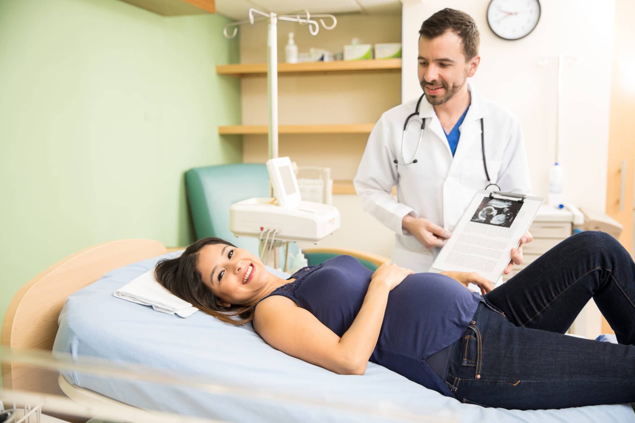 Médecin montrant à une femme enceinte son échographie dans un cabinet médical de gynéco.