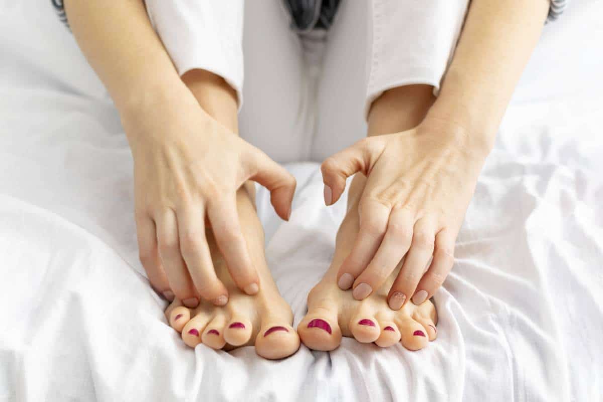 Personne comparant ses mains avec ses pieds, montrant le traitement du psoriasis des pieds, sur fond blanc.