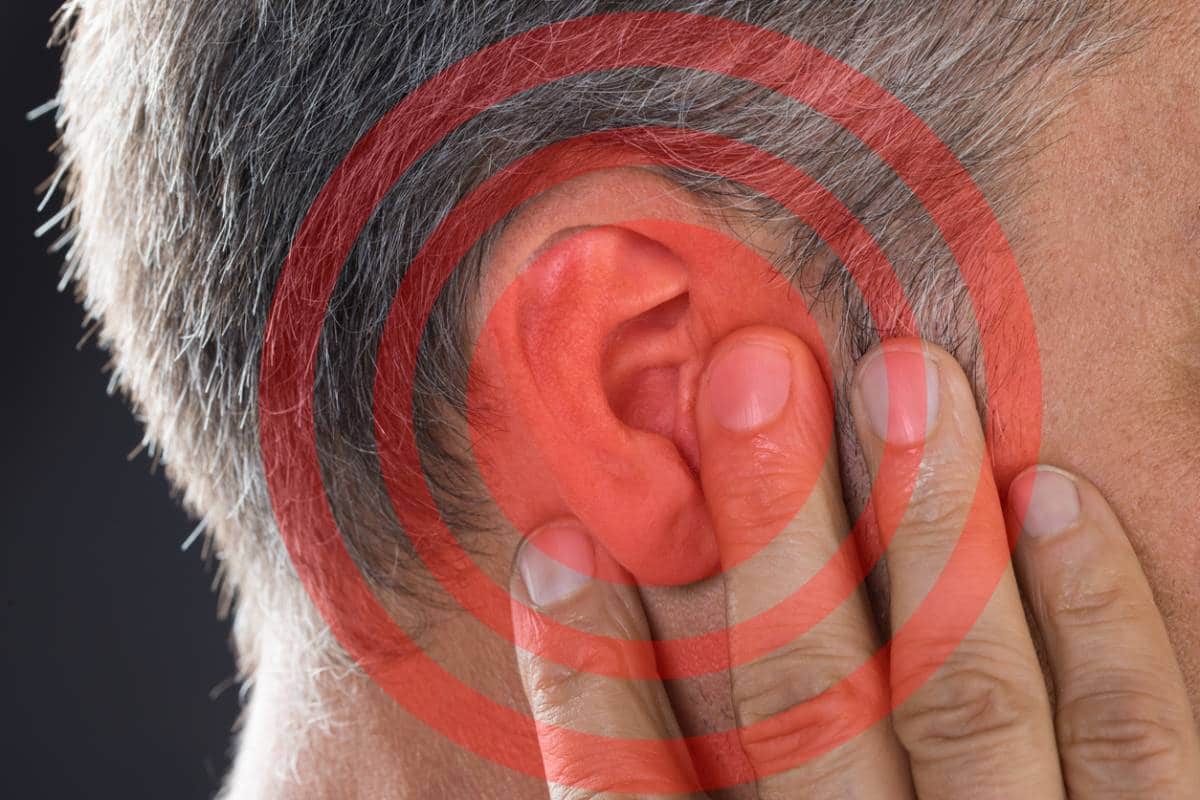 Gros plan d'une personne tenant sa main autour de son oreille avec des graphiques circulaires rouges indiquant une douleur ou un problème d'audition, nécessitant éventuellement des aides auditives.