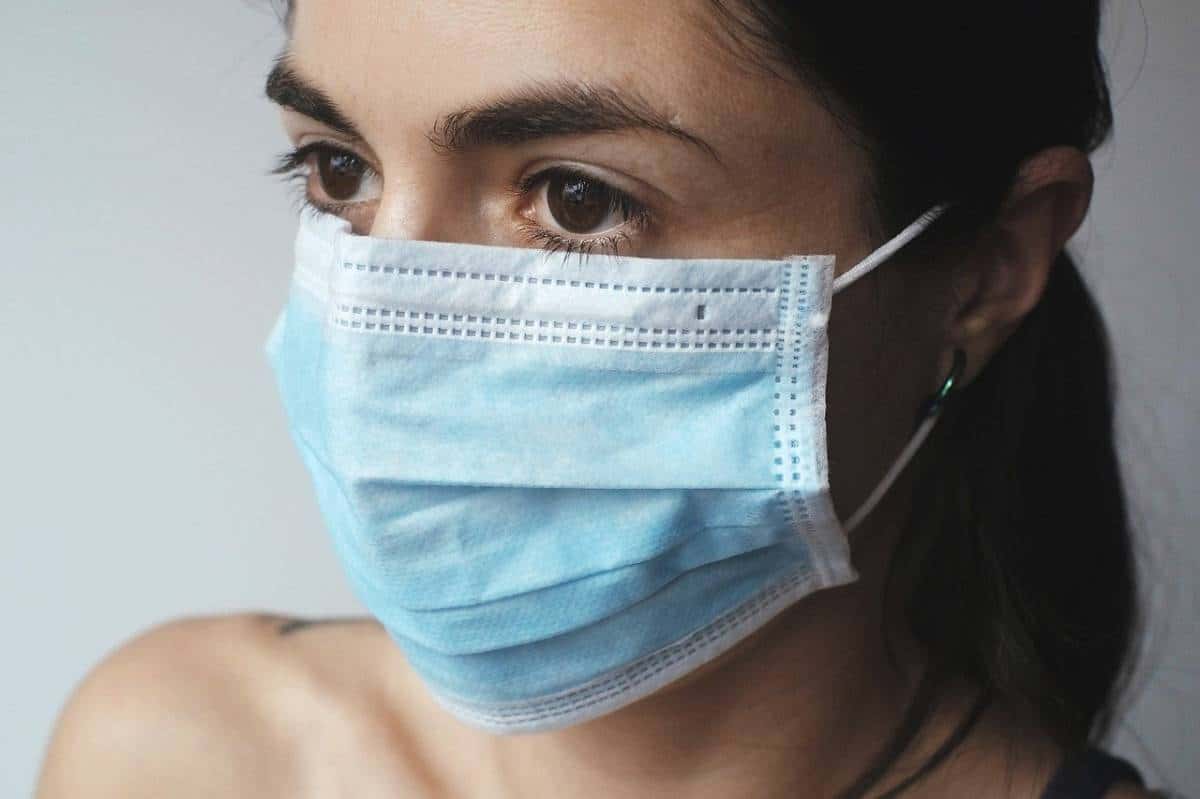 Femme portant un masque chirurgical couvrant son nez et sa bouche à cause du COVID-19.
