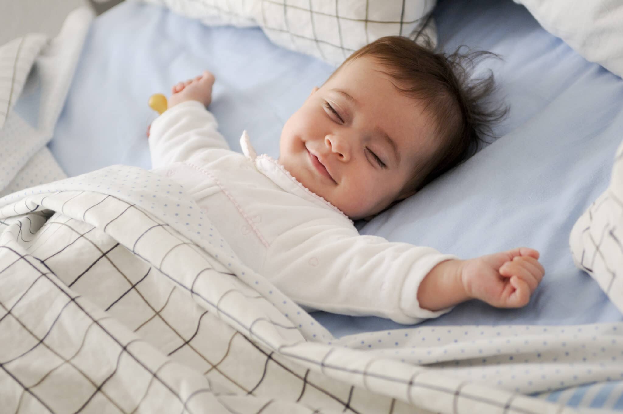Comment faire dormir bébé: Un infant reposant contentement dans un berceau, les bras étendus.