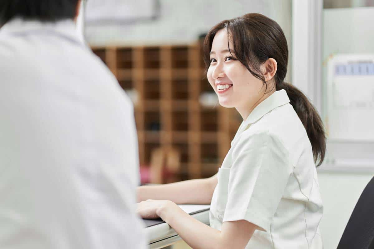 Une femme souriante engage une conversation avec un collègue recruteur dans un cadre de bureau.