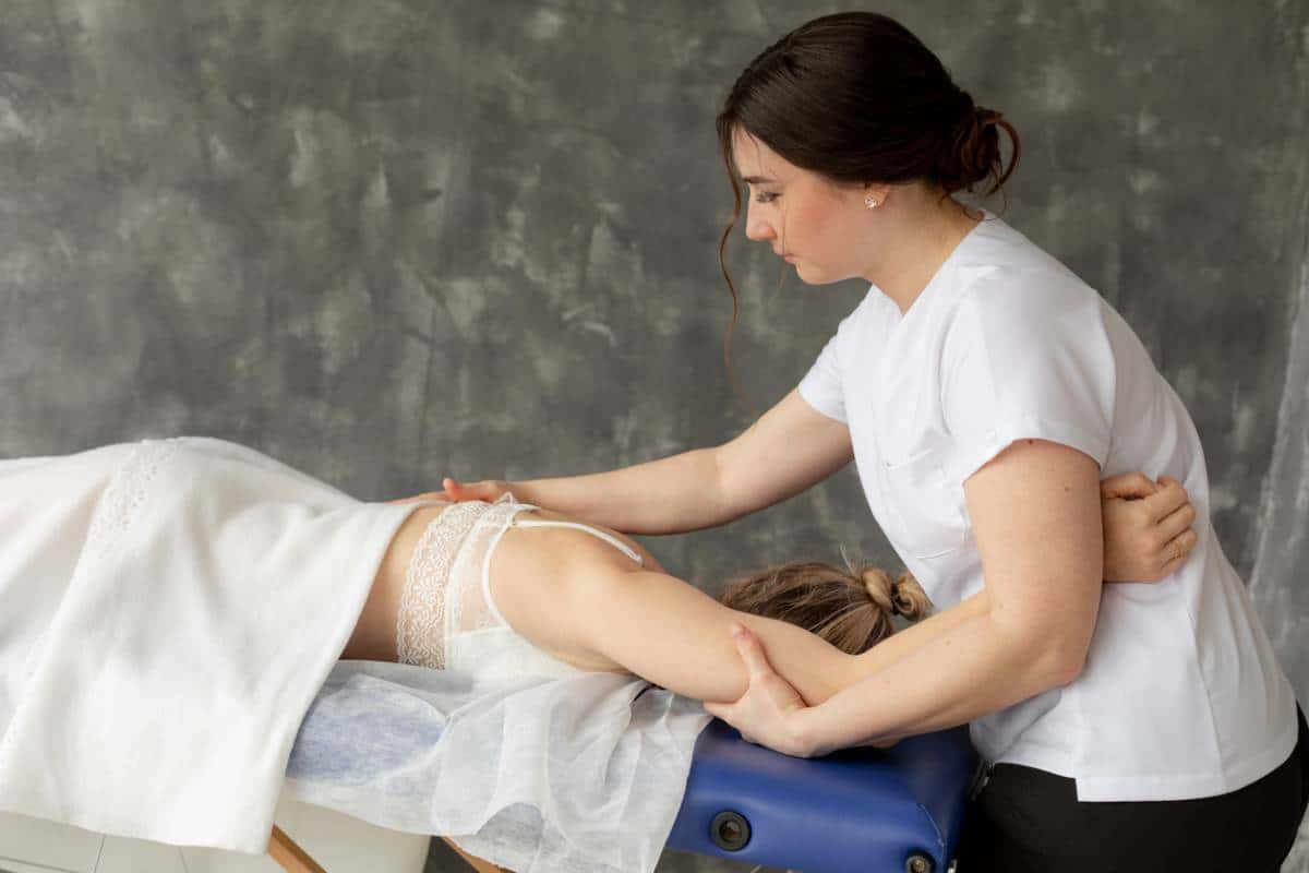 Un massothérapeute appliquant un massage du dos à un client allongé face contre terre sur une table de massage.