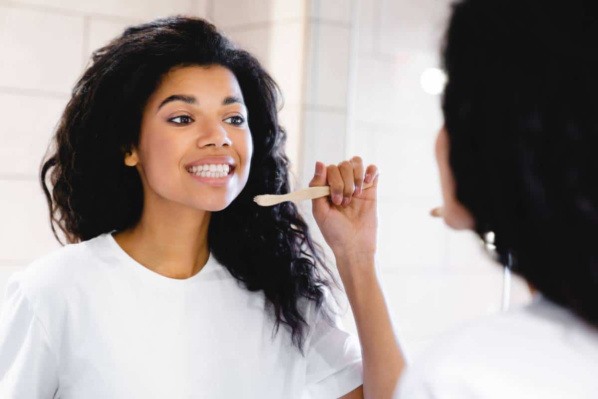 Femme se brossant les dents en regardant le miroir.
