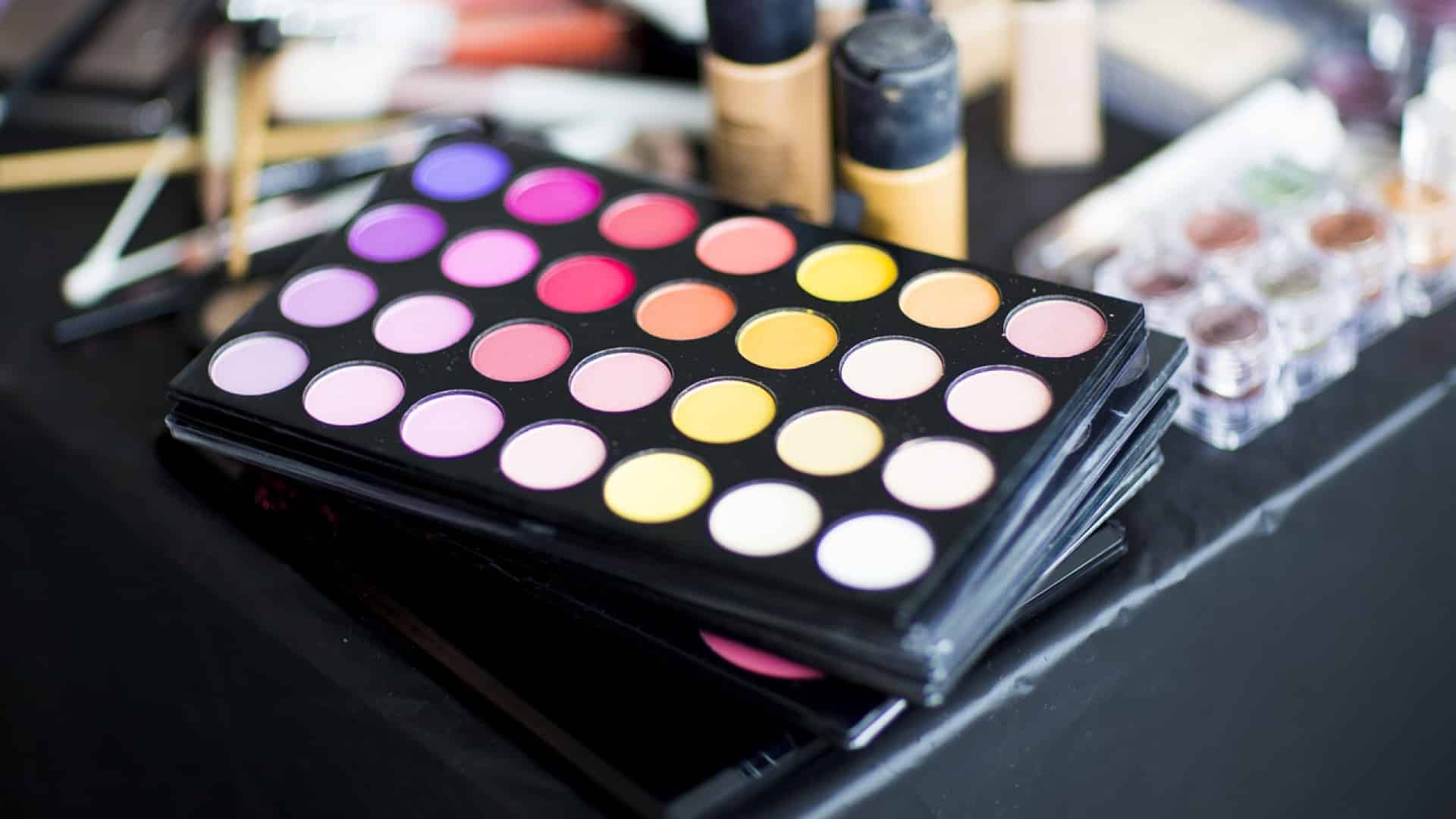 Une variété de produits de maquillage avec une palette de fards à paupières colorés au premier plan, présentant un atout majeur pour une analyse cosmétique par des