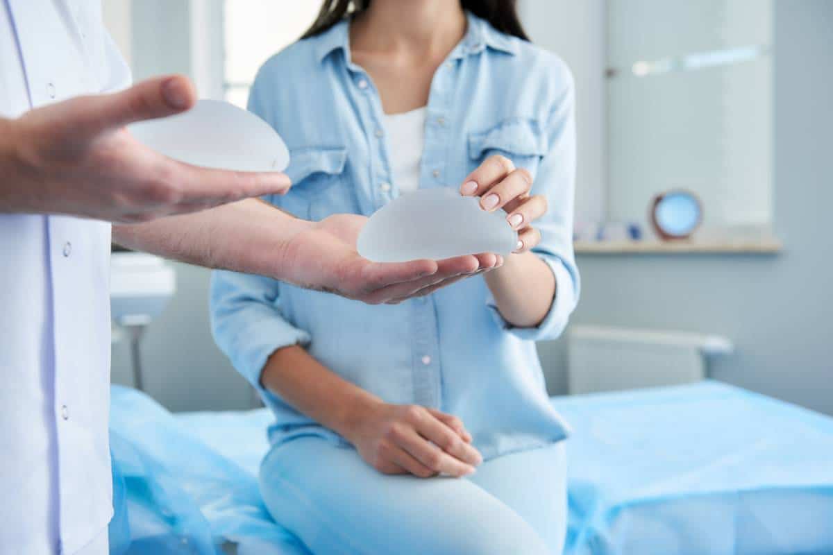 Médecin présentant un type d'implant pour augmentation mammaire à une patiente dans un cabinet médical.