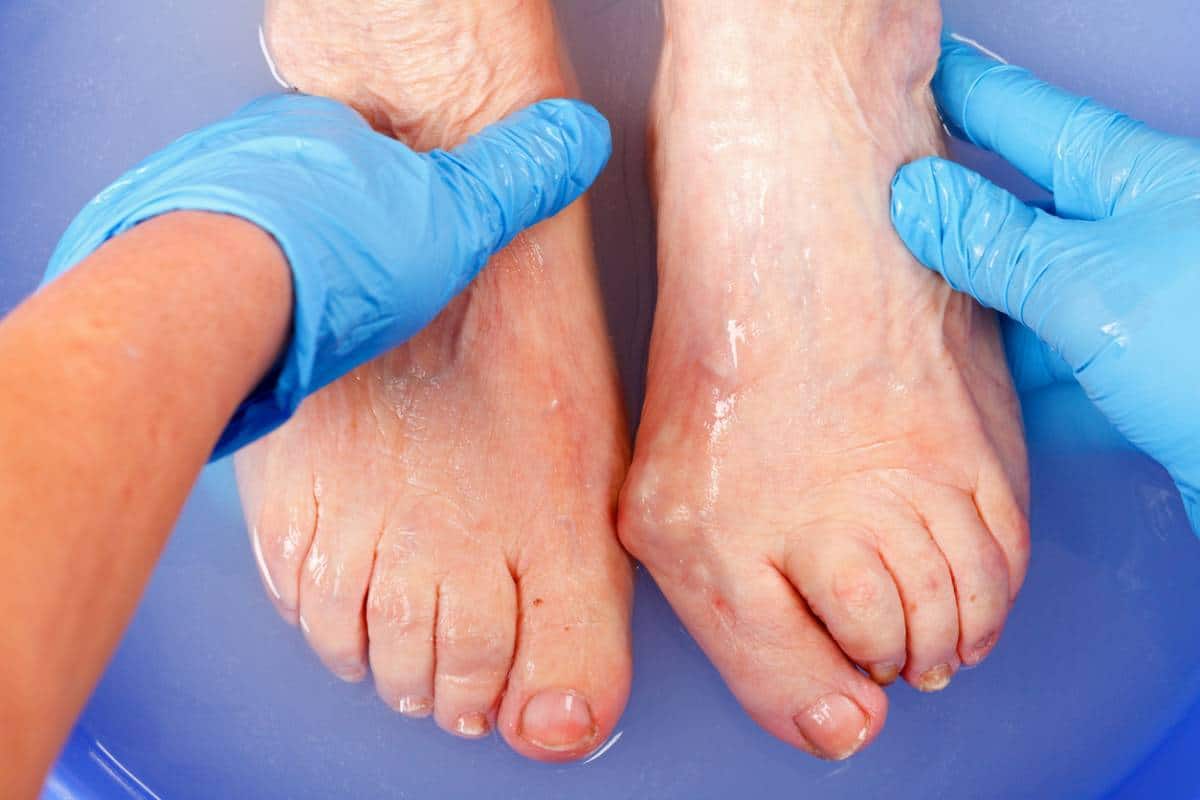 Podiatre examinant les pieds d'un patient pour évaluation médicale, spécialisé dans le soin des pieds après 60 ans.