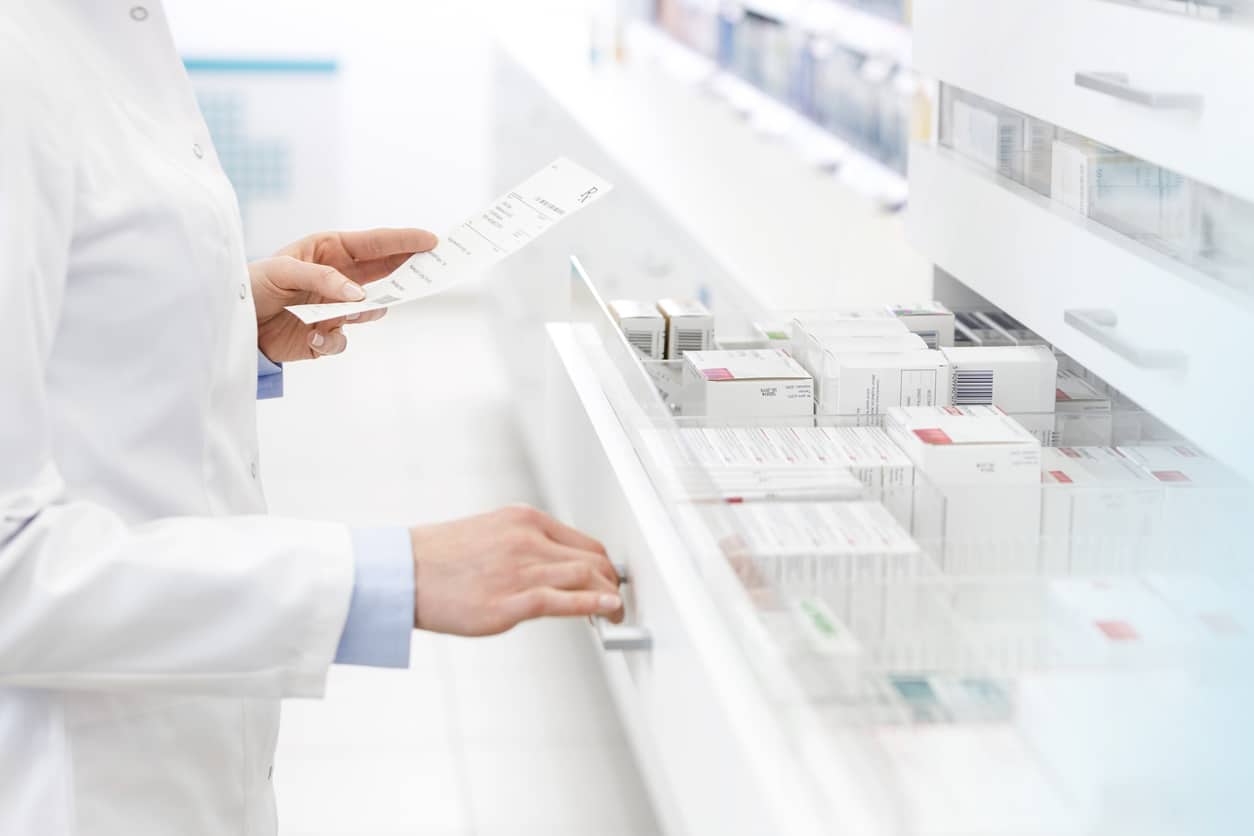 Pharmacien vérifiant une prescription dans une pharmacie pour des produits sensibles.