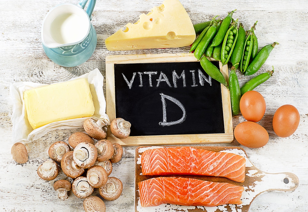 Divers aliments riches en vitamine D sont affichés sur une surface en bois à côté d'un petit tableau indiquant « vitamine D ».