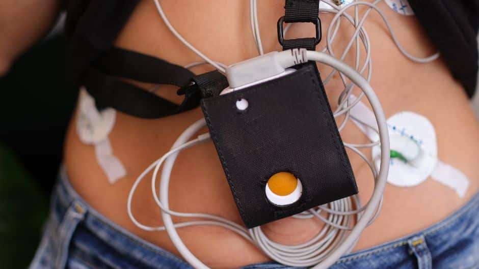 Une femme tient un appareil électronique sur le ventre.
