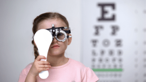 Une petite fille reçoit une correction au laser pour l'astigmatisme tout en regardant un tableau oculaire.