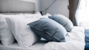 Un lit avec des oreillers bleus et blancs, parfait pour une nuit de sommeil.