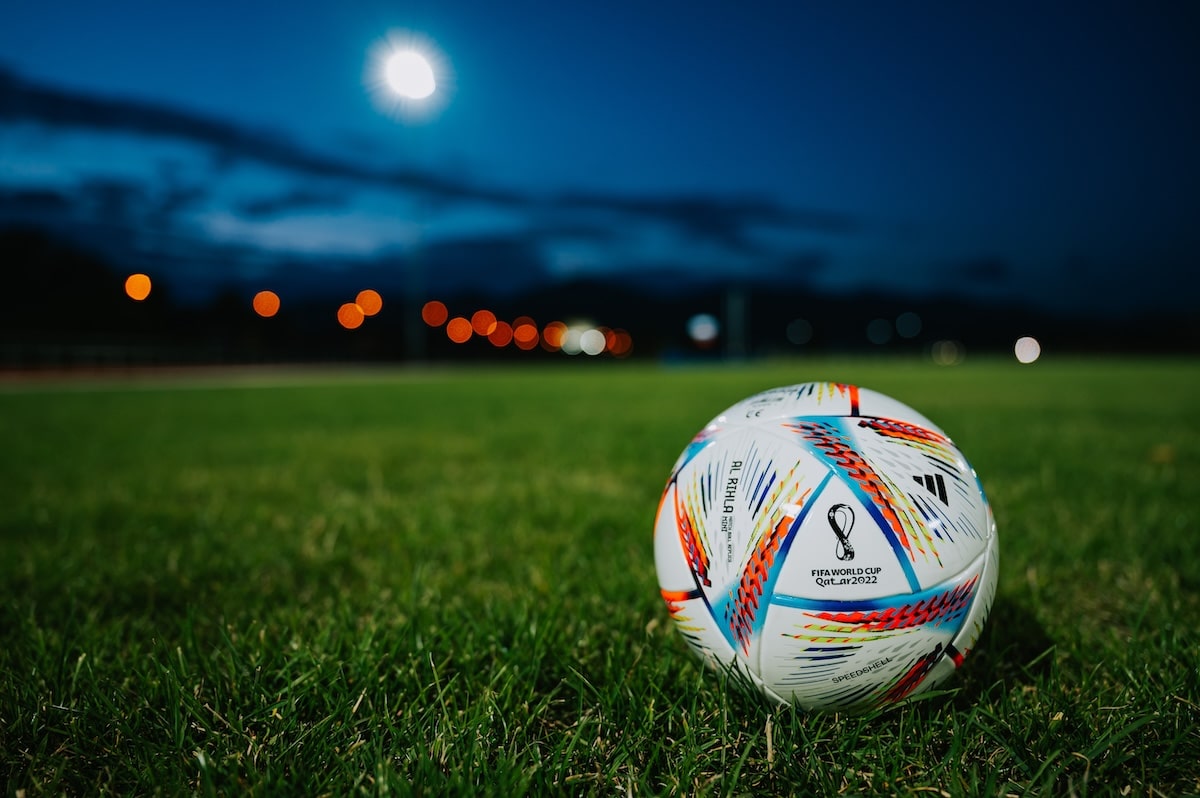Un ballon de football repose sur un terrain herbeux la nuit tandis que les équipes s'affrontent dans le virus de la FIFA, risquant de se blesser.