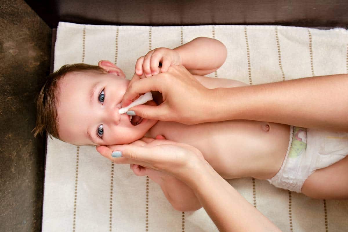 Une femme donne une brosse à dents à un nourrisson.